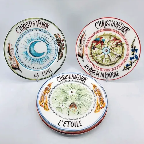 CHRISTIAN DIOR. Suite de 5 assiettes de table en porcelaine modèle Tarot comprenant : la Force, la Roue de la fortune, la Lune, Le soleil et l'Etoile. Diamètre : 26 cm.