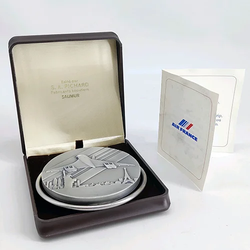AIR FRANCE CONCORDE. Pince à billets en bronze plaqué argent "Paris New York". Signée Pichard. Diamètre 7,2 cm. Circa 1980. Dans son écrin, et mot de remerciements Air France Vente PMDV 879 29/06/2025 Lot 7 50 - 70 € adjugé 110 €