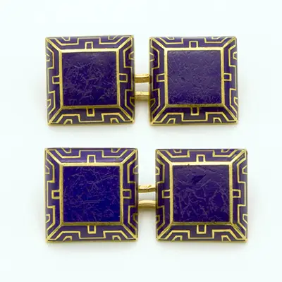 Cartier. Paire de boutons de manchette en or jaune 18K (750 millièmes) de forme carrée, bombée, au motif rehaussé d'émail bleu bordé d'une frise géométrique dorée. Epoque Art déco
