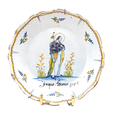 NEVERS, XVIIIe siècle . Assiette patronymique en faïence polychrome représentant Saint-Jacques. Inscription et date en dessous : "Jaque Fremie, 1784". Diam. 22.5 cm. Accidentée
