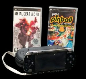 Sony - Console portable - PSP. Test d'allumage effectué avec succès - Version du logiciel 1.5, console débloquée toutes régions. Jeux associés : Metal Gear Ac!d et Pinball Classics. Avec cordon d'alimentation, notices, 2 pochettes de protection, alimentation allume-cigare, une paire d'écouteurs, un adaptateur double jack, un support Joycon, 2 protections CD pour les jeux.