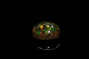 Opale noire cabochon ovale. Beaux éclats de couleur, dominante verte. 3.84 cts. 12.2mm x 10.0mm