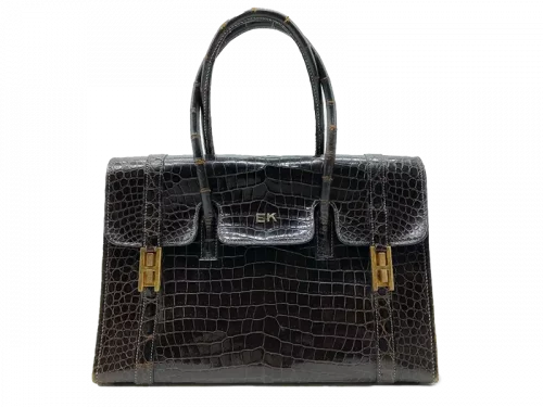 Sac à main "Drag" en crocodile porosus marron, intérieur en chèvre marron, bijouterie en métal plaqué or, chiffré EK sur le rabat (lettres en or 18K), L : 29,5 cm H : 21,5 cm (sans les anses). Circa 1965. Etat d'usage, usures aux angles et poignées, traces. Estimations : 800 € / 1000 €. Sac adjugé 2000 €